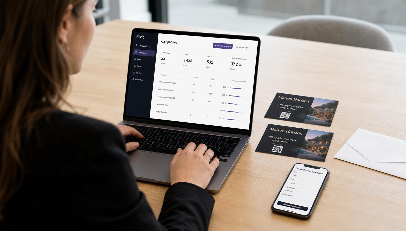 Une professionnelle consulte un tableau de bord Plirio sur son ordinateur portable, à côté de deux cartes postales immobilières avec QR code et d'un smartphone affichant une demande d'estimation.